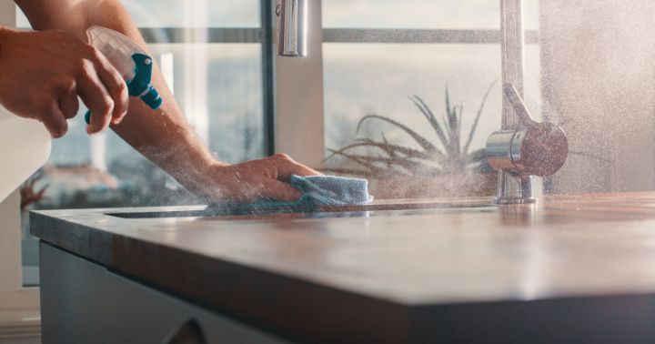 Persona utilizando agua ozonizada para limpiar la encimera de una cocina sin productos químicos