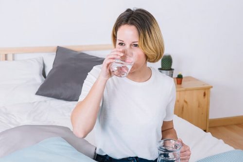 Mujer bebiendo agua de mineralización baja saludable para su riñón