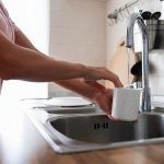 persona llenando vaso con agua del grifo osmotizada para consumo diario