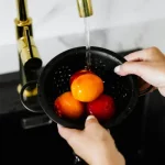 Familia llenando un vaso con agua purificada desde un sistema de ósmosis doméstico en la cocina