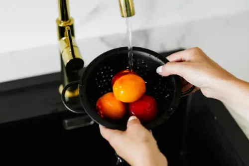 Familia llenando un vaso con agua purificada desde un sistema de ósmosis doméstico en la cocina