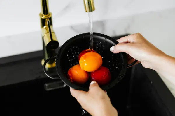 Familia llenando un vaso con agua purificada desde un sistema de ósmosis doméstico en la cocina